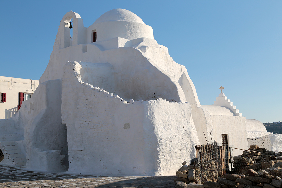 Mykonos.
Dans le quartier du Kastro, Ã  cÃ´tÃ© de la petite Venise, se dresse l'Ã©glise Panagia Paraportiani. Le charme incroyable qu'elle dÃ©gage est certainement dÃ» Ã  sa couleur blanche immaculÃ©e, et ses formes tout en rondeur. D'ailleurs, cette forme provient du fait que cette Ã©glise est constituÃ©e d'un assemblage de 5 chapelles diffÃ©rentes.
